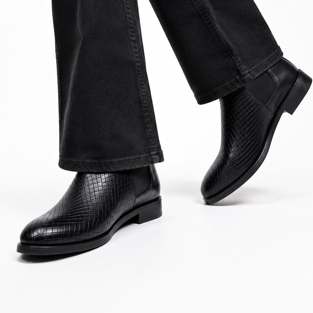 Black leather shoes worn with black pants on a white background